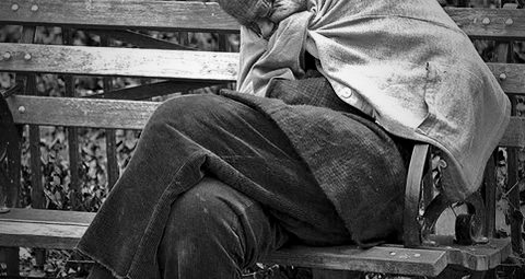 Man sitting on park bench trying to get warm