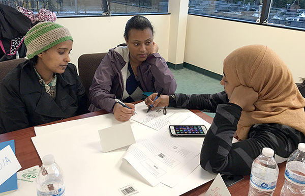Community Health Promoter Kedija Hashim (R) trains Lichi and Selamawit, two resident leaders from Windsor Heights, on event planning.