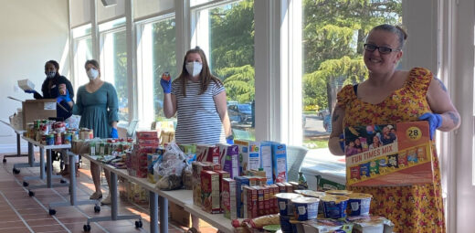 Resident Service staff smilling in masks behind food tables