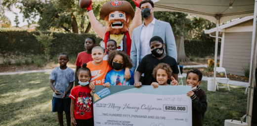 Arik posing with children and giant check
